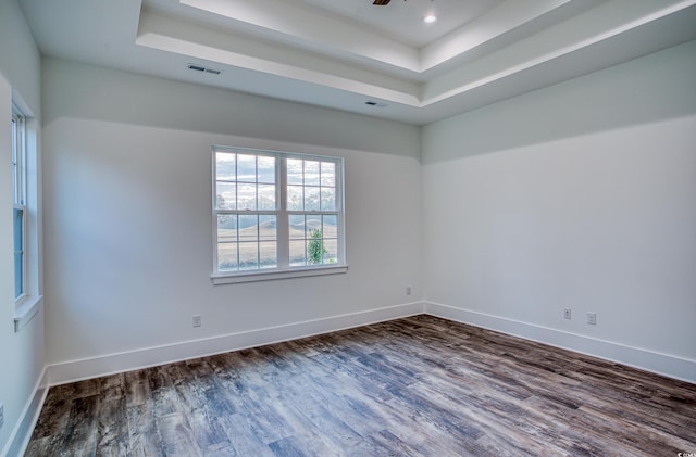 spare room featuring dark hardwood / wood-style floors, ceiling fan, and a tray ceiling