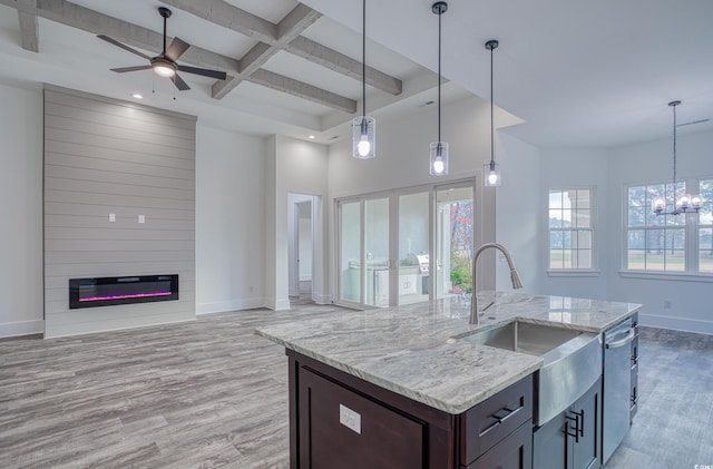 kitchen with ceiling fan with notable chandelier, light stone countertops, a fireplace, decorative light fixtures, and light hardwood / wood-style floors