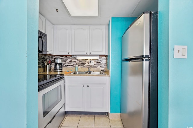 kitchen with appliances with stainless steel finishes, white cabinetry, tasteful backsplash, sink, and light tile patterned flooring