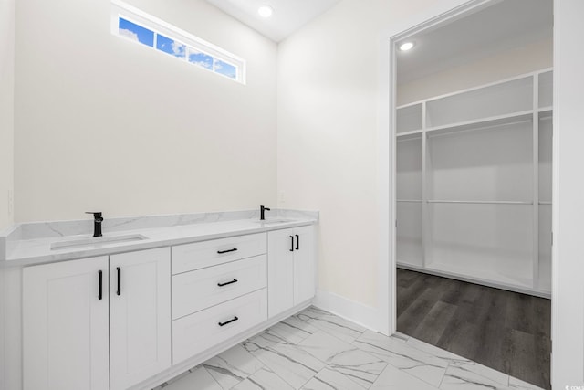 full bathroom with marble finish floor, a sink, and a walk in closet