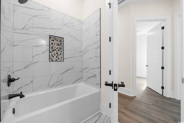 bathroom with baseboards, wood finished floors, and shower / bathtub combination