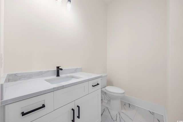 bathroom with toilet, marble finish floor, vanity, and baseboards