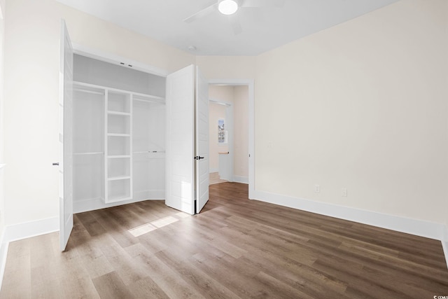 unfurnished bedroom featuring a closet, wood finished floors, a ceiling fan, and baseboards