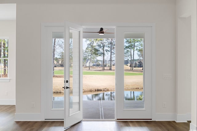 doorway featuring a water view, baseboards, and wood finished floors