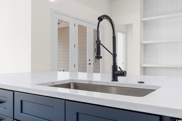 interior details featuring built in shelves, light stone counters, open shelves, and a sink