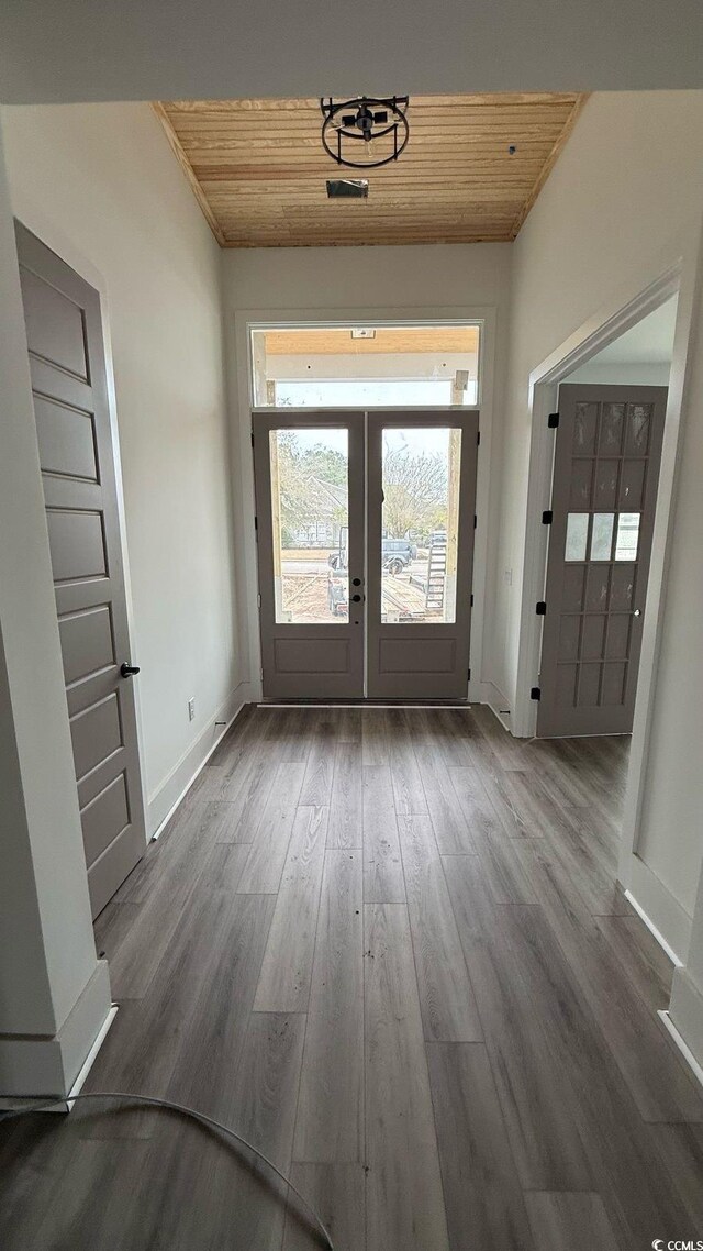 unfurnished living room featuring a large fireplace, baseboards, built in features, a raised ceiling, and dark wood-type flooring