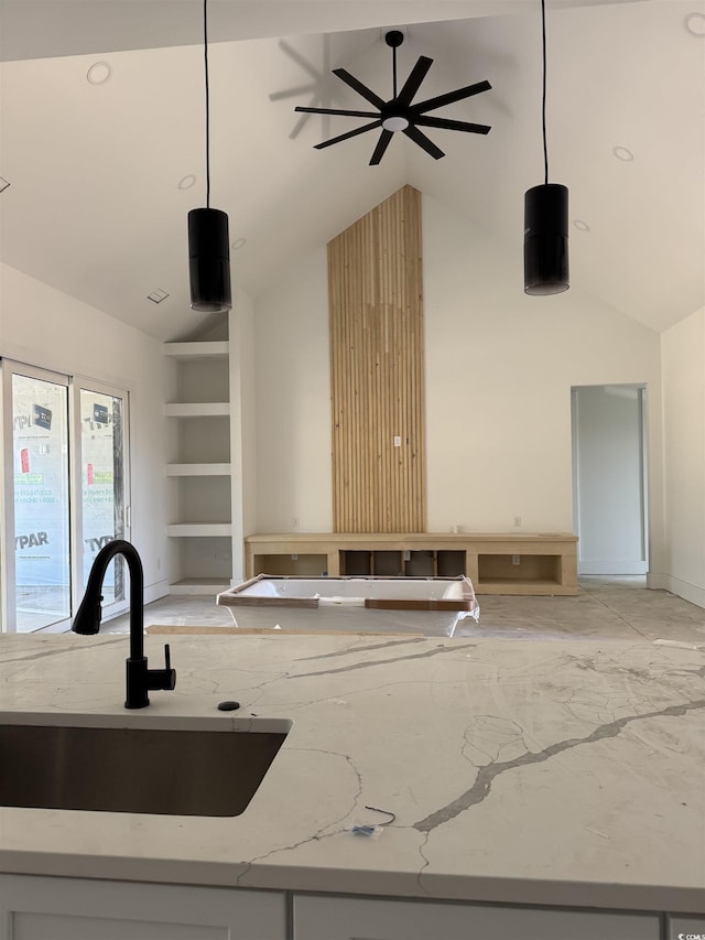 interior space with high vaulted ceiling, a sink, light stone countertops, and pendant lighting