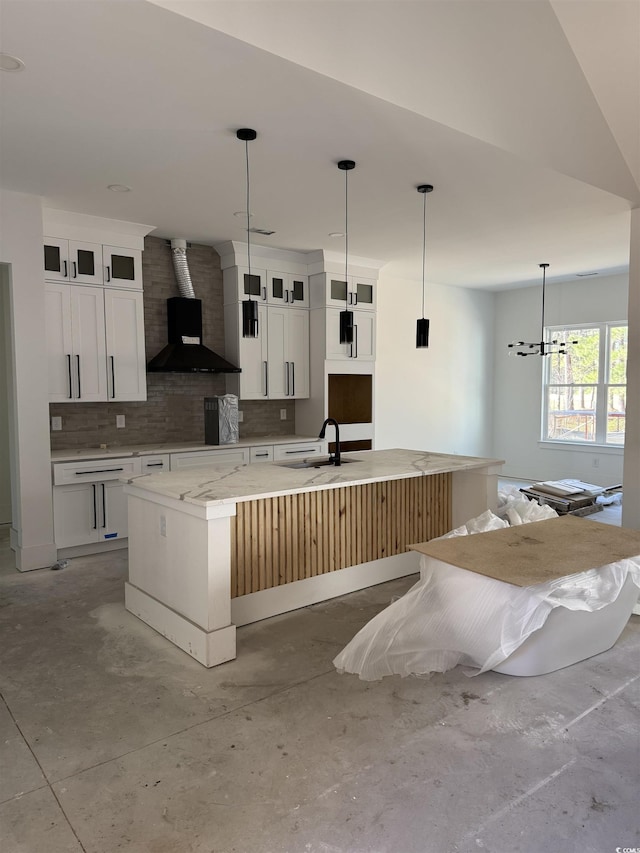 kitchen featuring tasteful backsplash, a large island with sink, white cabinets, and wall chimney range hood