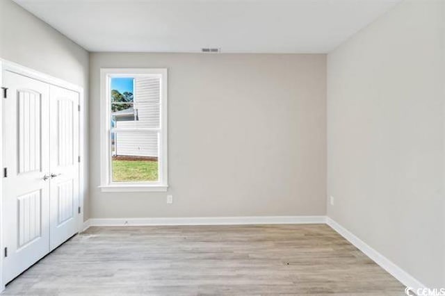 296 Starlit Way, Myrtle Beach, SC 29579 - unfurnished bedroom featuring light wood-type flooring, multiple windows, a closet, and baseboards