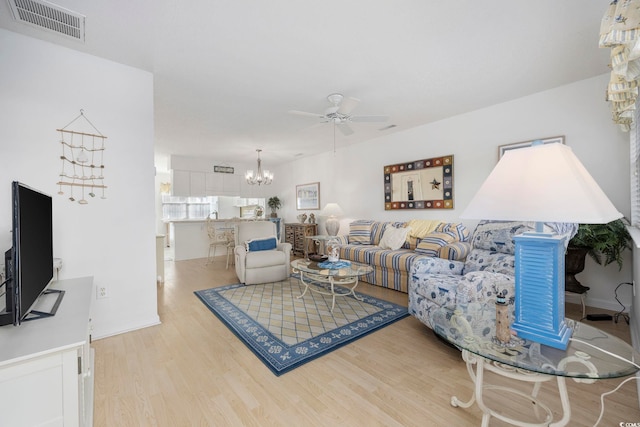 living room featuring ceiling fan with notable chandelier and light hardwood / wood-style floors