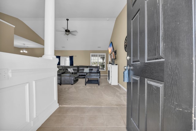 entrance foyer featuring ceiling fan with notable chandelier, light colored carpet, lofted ceiling, and decorative columns