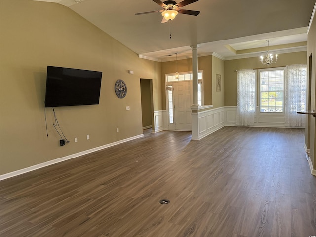 unfurnished living room with crown molding, dark wood-style flooring, decorative columns, a wainscoted wall, and ceiling fan with notable chandelier