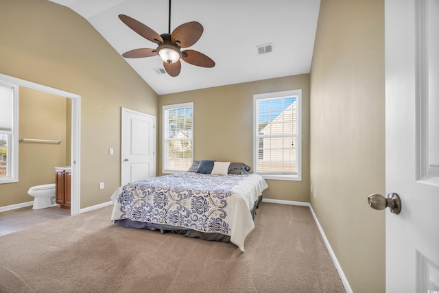 bedroom featuring ceiling fan, light colored carpet, lofted ceiling, and connected bathroom