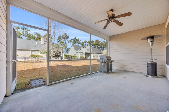 unfurnished sunroom with a ceiling fan, a wealth of natural light, and a residential view