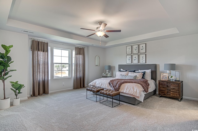 bedroom with light carpet, baseboards, visible vents, and a raised ceiling