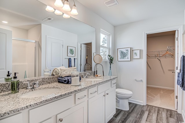 full bath with double vanity, visible vents, a spacious closet, a stall shower, and a sink