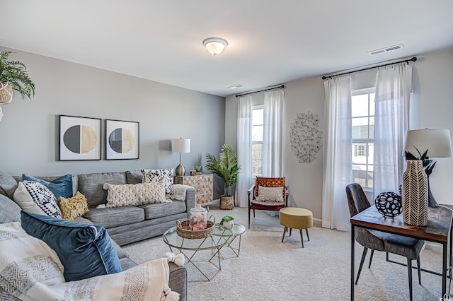 living area featuring light colored carpet, visible vents, and baseboards