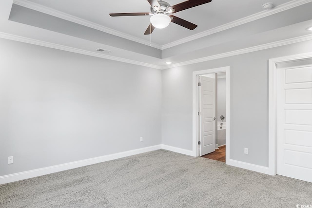 unfurnished bedroom with ensuite bathroom, ornamental molding, carpet flooring, a raised ceiling, and ceiling fan