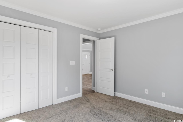 unfurnished bedroom with ornamental molding, a closet, and carpet flooring