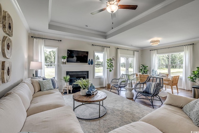 living room with a tray ceiling, ornamental molding, ceiling fan, and hardwood / wood-style flooring