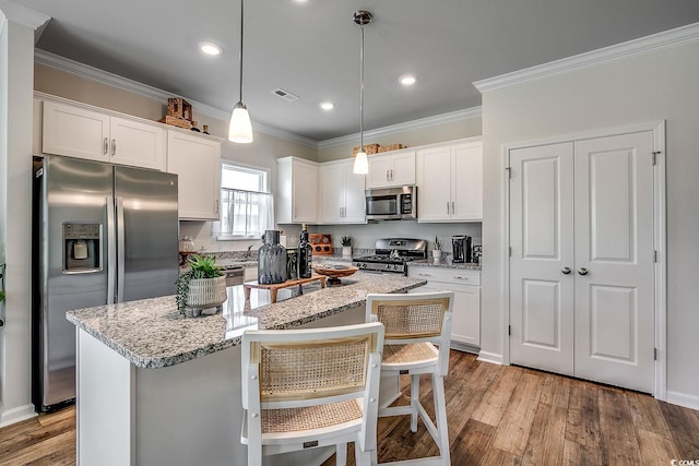 kitchen featuring white cabinetry, a center island, hanging light fixtures, a kitchen breakfast bar, and stainless steel appliances