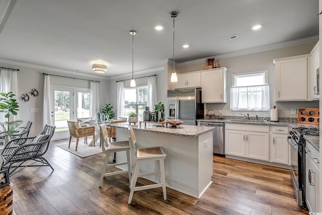 kitchen featuring white cabinetry, appliances with stainless steel finishes, a kitchen island, and pendant lighting