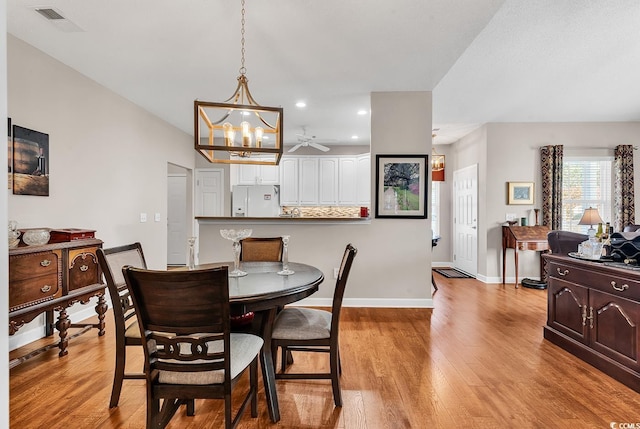 dining space with light wood-type flooring and ceiling fan with notable chandelier