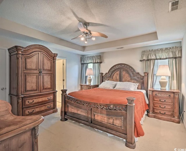 carpeted bedroom featuring ceiling fan, a textured ceiling, and a tray ceiling