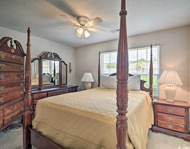 carpeted bedroom featuring ceiling fan and a textured ceiling