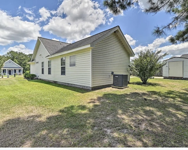 view of side of home featuring a yard, central air condition unit, and a storage unit