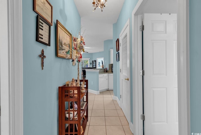 corridor featuring light tile patterned floors and a notable chandelier