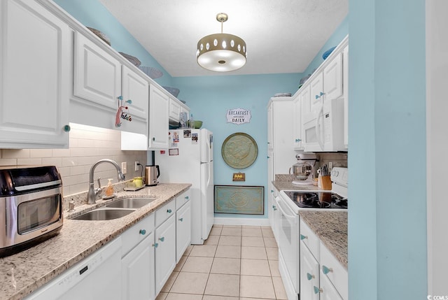 kitchen with white appliances, sink, decorative light fixtures, light tile patterned flooring, and white cabinetry