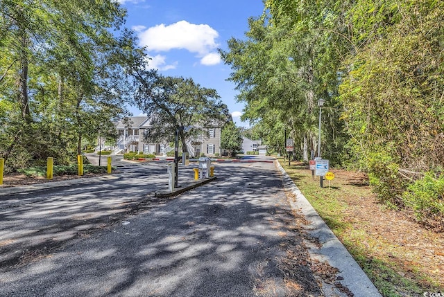 712 Algonquin Dr Unit A, Pawleys Island, SC 29585 - view of asphalt road featuring traffic signs, street lights, curbs, a gated entry, and a residential view