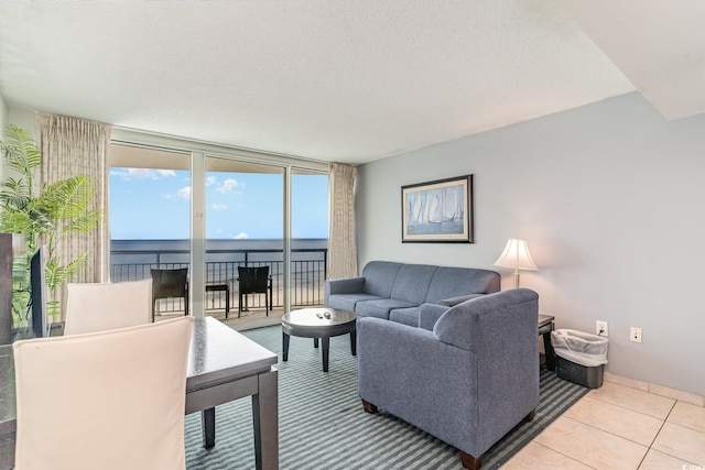 living room featuring expansive windows, a water view, light tile patterned flooring, and a textured ceiling