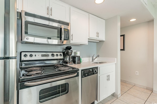 kitchen with white cabinets, stainless steel appliances, light tile patterned flooring, and sink