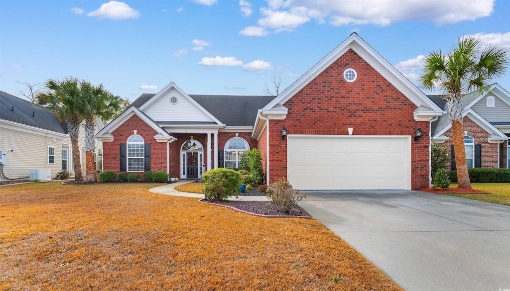 view of front of house with a front lawn, a garage, and cooling unit