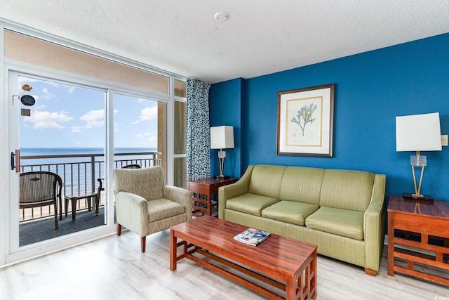 living room with a textured ceiling, a water view, and light hardwood / wood-style floors