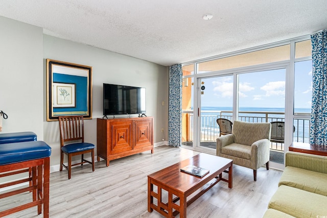 living room with a textured ceiling, light hardwood / wood-style flooring, and a wall of windows