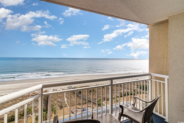 balcony featuring a view of the beach and a water view