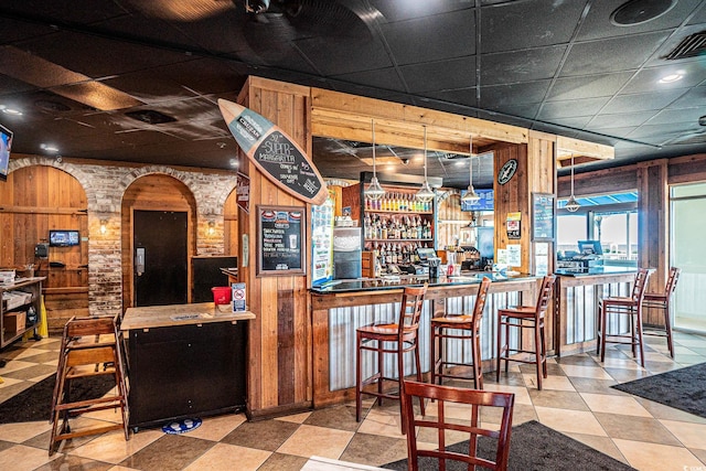 bar featuring a paneled ceiling and wood walls