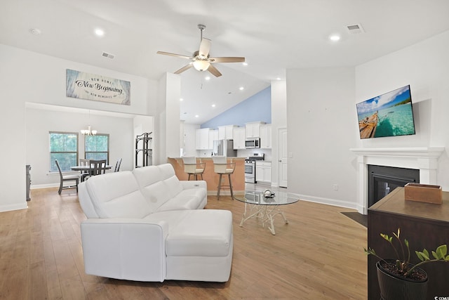 living room featuring ceiling fan, light hardwood / wood-style floors, and high vaulted ceiling