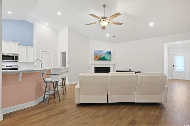 living room featuring ceiling fan, dark hardwood / wood-style floors, sink, and high vaulted ceiling