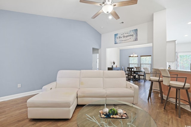 living room with lofted ceiling, ceiling fan with notable chandelier, and hardwood / wood-style floors