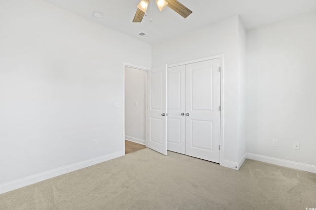 unfurnished bedroom featuring ceiling fan, light carpet, and a closet