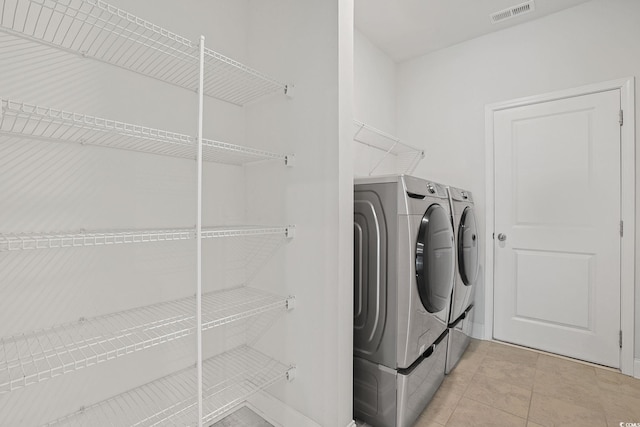 laundry area with light tile patterned floors and washing machine and clothes dryer