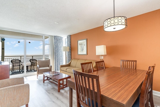 dining area with wood-type flooring, a textured ceiling, a water view, and expansive windows