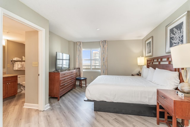 bedroom with ensuite bathroom and light hardwood / wood-style floors