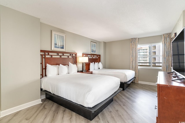 bedroom with a textured ceiling and light hardwood / wood-style flooring