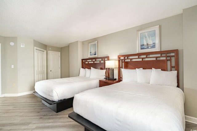 bedroom with multiple closets and light hardwood / wood-style flooring