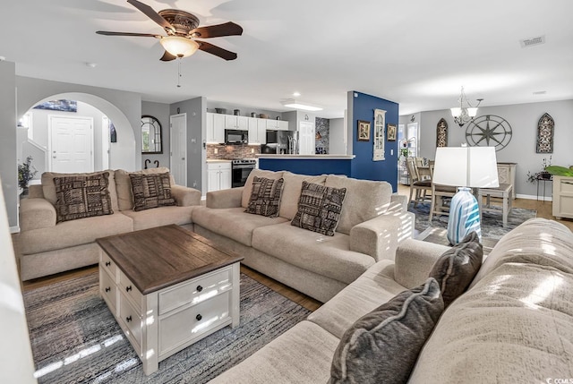 living room with dark wood-type flooring and ceiling fan with notable chandelier